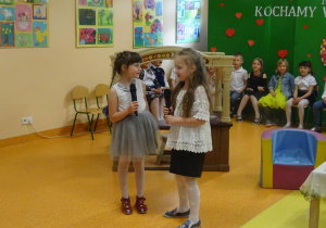 Dwie dziewczynki trzymają w ręku mikrofon, recytują wiersze.
